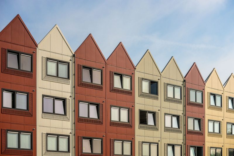 A vibrant row of gable-roofed residential buildings with metal facades